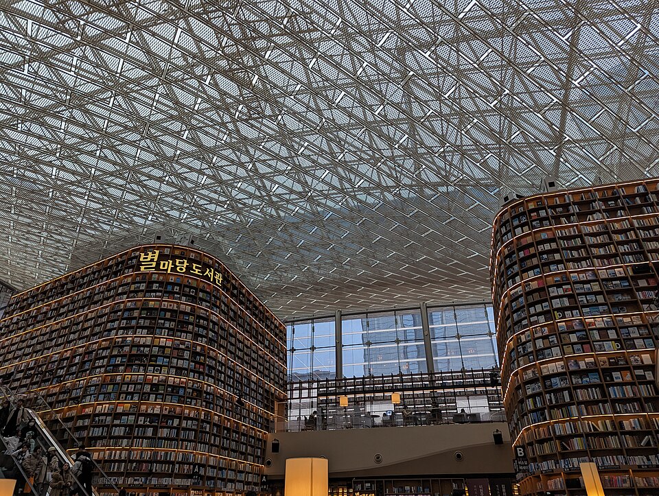 The towering, illuminated bookshelves of Starfield Library inside COEX Mall, Seoul, filled with books and surrounded by visitors.